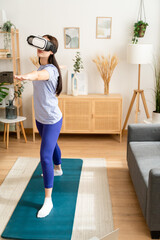 Woman training at home while watching lesson with virtual reality glasses.