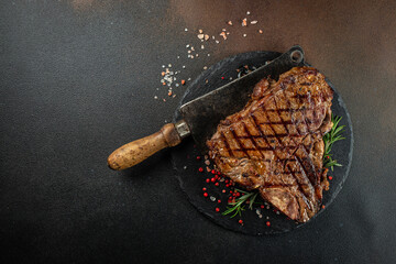 T-bone grilled beef steak with spices on a dark background. Restaurant menu, dieting, cookbook...
