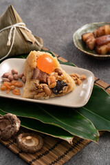 Zongzi, rice dumpling for Dragon Boat Festival on dark gray table background with ingredient.