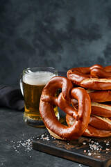 Oktoberfest concept card. Traditional Bavarian pretzels with beer bottle mug on old dark black rustic background. Perfect for Octoberfest. Oktoberfest food menu.