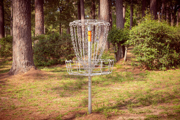 Disc Golf hole basket in city park with forest in the background. Also known as Frisbee Golf.