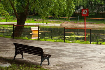 A bench by a pond in a small city park. The sign says: Swimming is prohibited.
