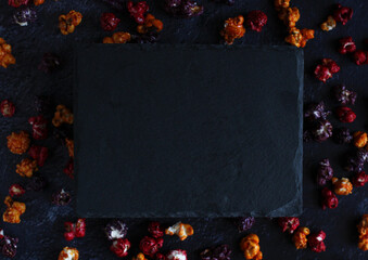 black board on a background of colored popcorn in caramel glaze with copy space