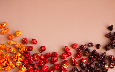 Multi-colored popcorn in caramel glaze scattered in rows on a pink background
