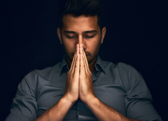 Night, worship and man with hands praying in studio to God, Jesus Christ or spiritual healing on black background. Holy, gratitude and thank you by christian male in prayer for help, hope and trust - obrazy, fototapety, plakaty