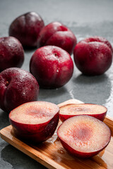 Some cut plums and other plums arranged to the background.