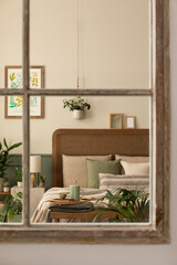 Interior design of bedroom interior with mock up poster frame, cozy bed, beige bedding, plants in flowerpots, stylish wooden bench, lamp and personal accessories. Home decor. Template.