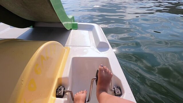 Woman floating on catamaran. Person pedaling with her feet and swimming on catamaran on sea surface with waves on sunny summer day. Active lifestyle recreation leisure sport POV