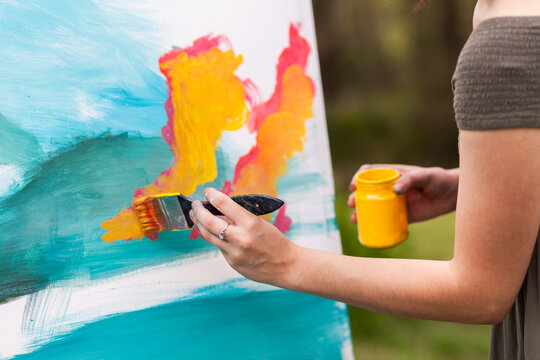 Artist with brush beginning an acrylic painting on canvase