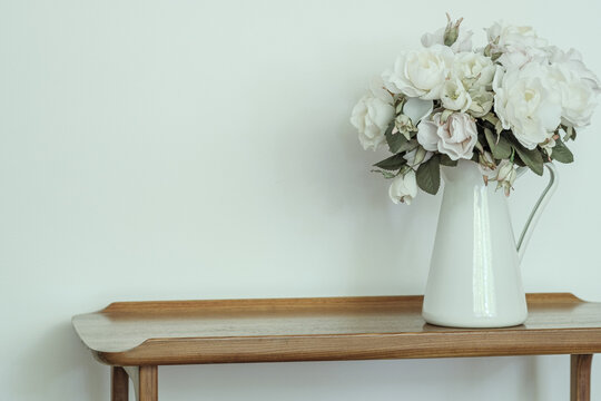 White Roses in a white vase on a timber hallway table inside a country home