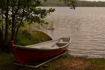 Naklejka na ściany i meble wooden boat on the lake shore, Finnish summer forest