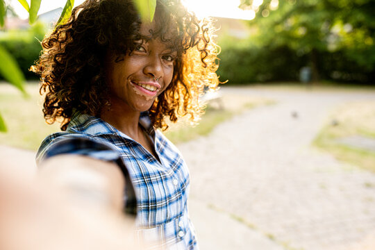 young biracial woman taking selfie on sunset outside, female person with genetic vitiligo smiling at the camera, happy people and body positive concepts
