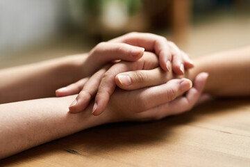 Comfort, holding hands and support of friends, care and empathy together on table after cancer....