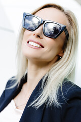 Portrait of sexy stylish woman standing in the street in black suit, wearing sunglasses on sunny spring day