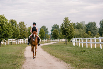 Young woman and her beautiful red horse during calm trail ride. Ecotourism and animal care concepts.