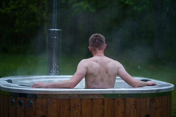 Man relax in outside hot tub SPA surrounded by trees and forest