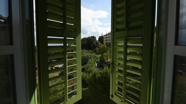 Open window with green wooden shutters with view of the Lovran, travel destination at Istrian seaside in Croatia