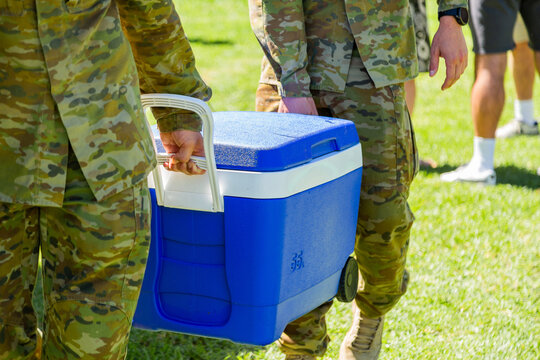 Army men carrying an esky full of ice blocks at army event