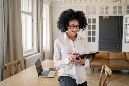 A young woman in an office in a white shirt uses a tablet for analytics records data. - Powered by Adobe