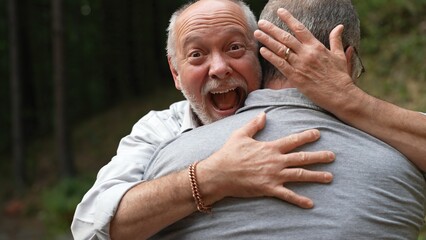 Two gay men hugging with smiles and happiness showing engagement ring for marriage proposal.