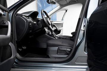 Modern black car interior, leather steering wheel, climate control, navigation, deflectors on the car panel. Details interior. 