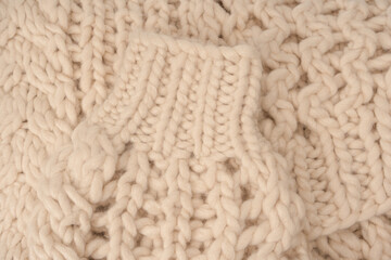 A fragment of beige knitted fabric, knitted from white sheep wool.
