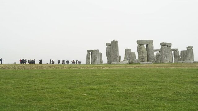 Tourists milling around Stonehenge on foggy spring day