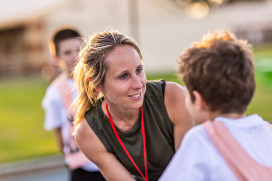 netball coach bending to talk to young player