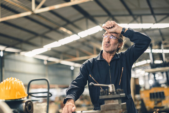 Tired sweat senior adult engineer worker hard work fatigue male staff in metal factory hot weather