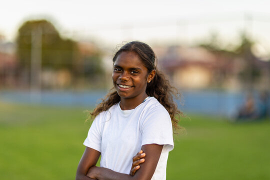aboriginal girl wearing white tee-shirt and looking at camera with arms crossed