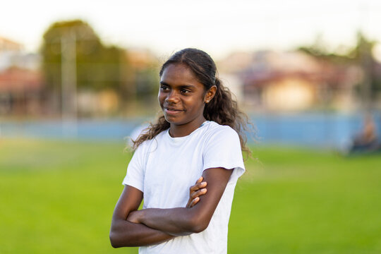 one aboriginal girl standing with arms crossed with blurry background