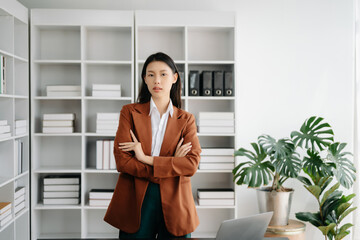 Young attractive Asian female office worker business suits smiling at camera in modern office .