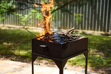 BBQ Barbecue Charcoal Fire Grill. Selective focus. Close-up empty flaming charcoal grill with open...