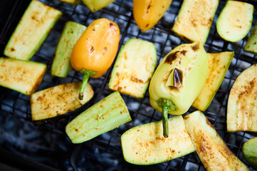 Selective focus. Top view grilled bell pepper and sliced zucchinis over charcoal in the barbecue grill. Close-up. The concept of summer and weekend outdoors leisures. Picnic in the nature or backyard