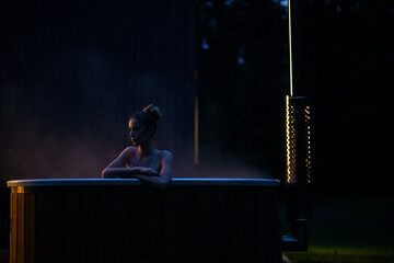 Woman relax in outside hot tub at night. Cinematic view