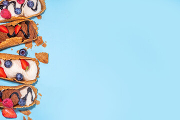 Various sweet taco ice creams. Waffle taco shells with chocolate and vanilla flavour ice cream with different fruits, berry, toppings