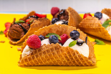 Various sweet taco ice creams. Waffle taco shells with chocolate and vanilla flavour ice cream with different fruits, berry, toppings
