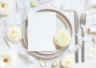 Wedding table setting with card near cream roses and white silk ribbons top view, mockup