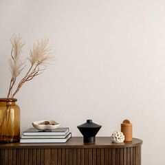 Minimalist composition of living room interior with copy space, wooden commode, vase with dried flowers, candle, black books and personal accessories. Home decor. Template.