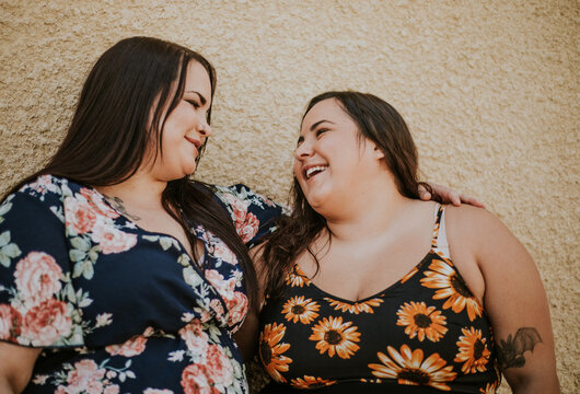 closeup of 2 plus size Metis women smile and look at each other