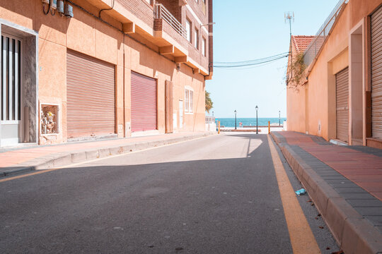 Fototapeta Spanish street view with terracotta house facades under blue sky - vacation in Spain  