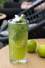 Fresh mojito and limes on a street cafe table. Summer cooling alcohol cocktail