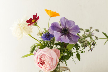 Stylish colorful flowers bouquet on rustic wall background. Beautiful summer wildflowers, anemones...