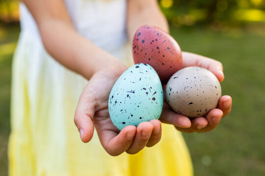 Child holding out speckled Easter eggs in hand
