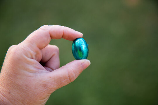 easter egg in blue foil being held by fingertips