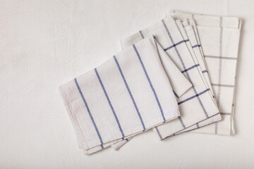 Kitchen cotton towels with a simple pattern folded on a white textured table. Kitchenware. Kitchen...