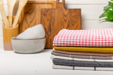 Checked cotton kitchen towels folded on a light kitchen table. Kitchenware. Kitchen towel or...