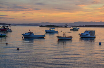 Fototapeta premium fishing boats and Zeki Muren island in Ildir Bay harbor at sunset (Cesme, Izmir province, Turkiye) 
