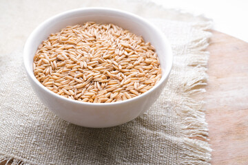 oat seeds in a round bowl isolated on wooden background top view