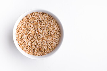 oat seeds in a round bowl isolated on wooden background top view